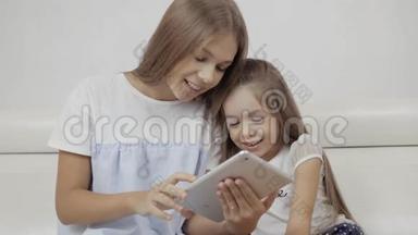 两个<strong>姐姐</strong>看着平板电脑，坐在沙发上玩游戏，<strong>小</strong>婴儿和成年妹妹